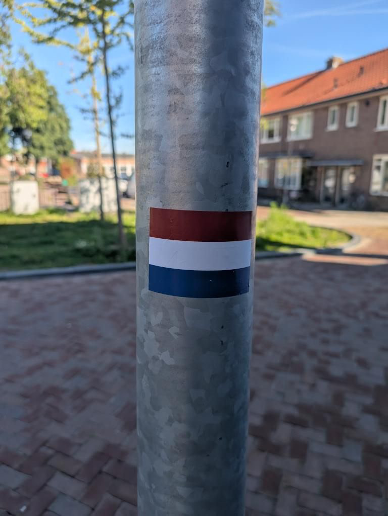 Geplakte sticker van een nederlandse vlag op een lantarenpaal | HeelHollandPlaktt